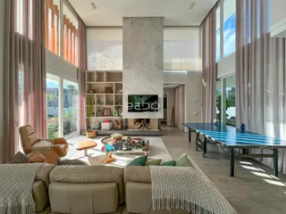 Sala de estar moderna com grandes janelas e lareira em um imóvel no Brasil.
