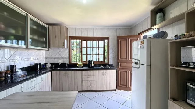 Imagem de uma cozinha com armários de madeira e revestimento de cerâmica.