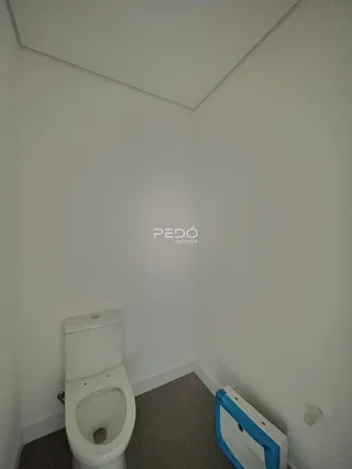 Foto de um ambiente interno mostrando um vaso sanitário e a parede branca.