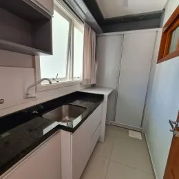 Foto de uma cozinha com bancadas escuras e armários brancos.