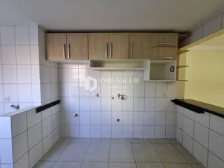 Foto de uma cozinha com revestimento branco e armários de madeira clara.