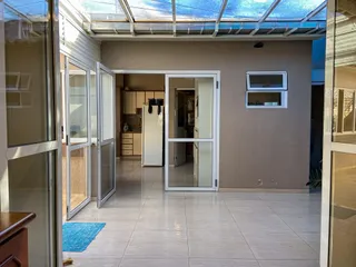 Área comum com piso de cerâmica e portas de vidro que dão acesso ao exterior.