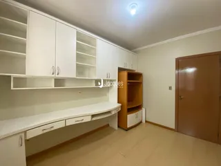 Foto de um ambiente interno com armários brancos e piso de madeira clara.