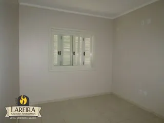 Parede interna branca com uma janela em uma residência.