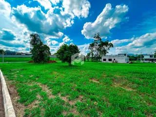Vista externa de um terreno com gramado e árvores ao fundo.