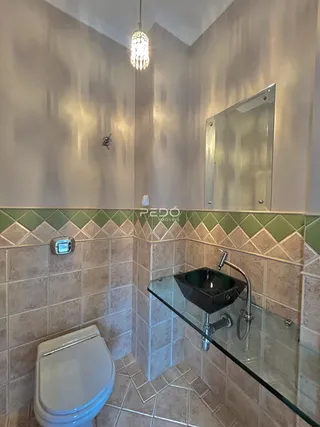 Banheiro com revestimento cerâmico e bancada de vidro.