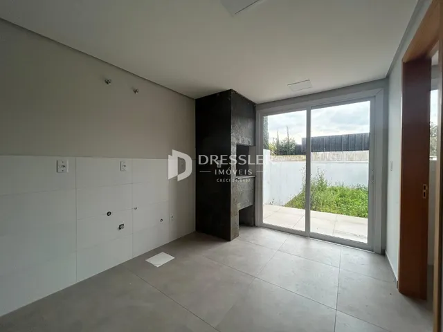 Interior de um ambiente com paredes brancas e piso de concreto em uma residência.