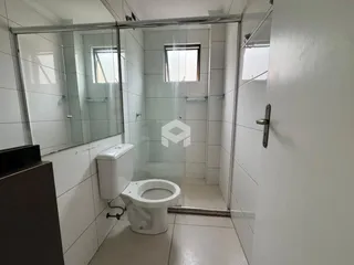 Interior de um banheiro com revestimento branco e box de vidro.