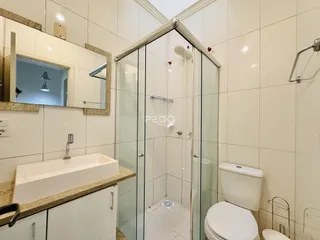 Foto de um banheiro com box de vidro e louças brancas.