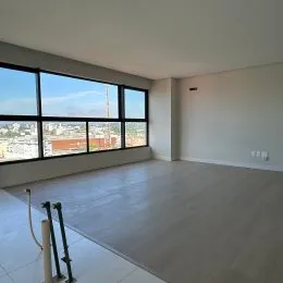 Vista de uma sala ampla com grandes janelas que oferecem iluminação natural.