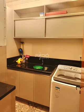 Foto interna de uma cozinha com armários brancos e máquina de lavar roupa.
