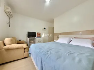 Quarto com cama grande e sofá em ambiente claro.