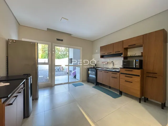 Ambiente interno de uma sala de estar com cozinha aberta e acesso a um pátio.