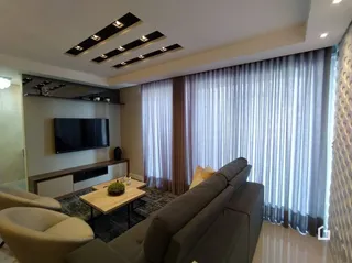 Sala de estar com sofá e cortinas claras.