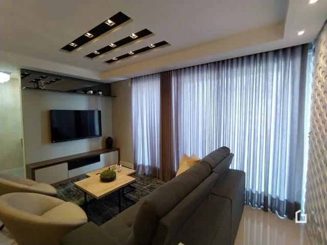 Sala de estar com sofá e cortinas claras.