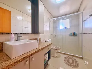 Foto interna de um banheiro com azulejos brancos e bancada de granito.