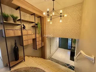 Hall de entrada com escadaria e estantes de madeira na residência.