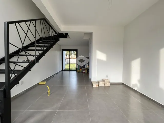 Hall de entrada com piso de cerâmica e escada preta.