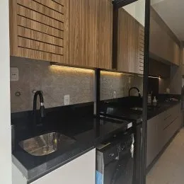 Foto de um ambiente de cozinha com armários de madeira e bancadas escuras.