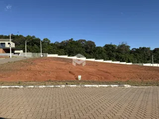 Vista da propriedade com terra avermelhada e muro de contenção.