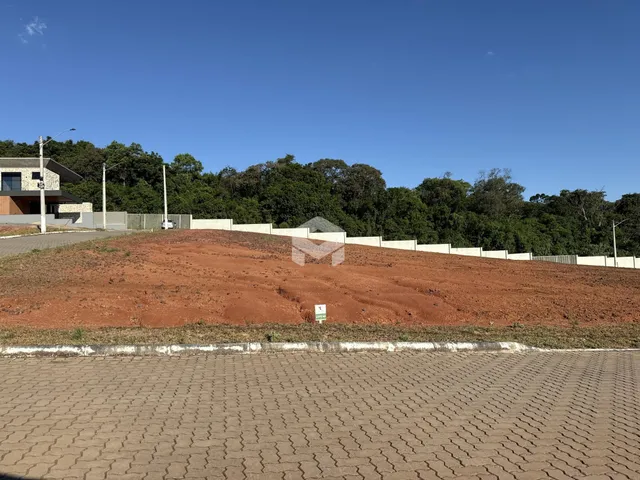 Vista da propriedade com terra avermelhada e muro de contenção.