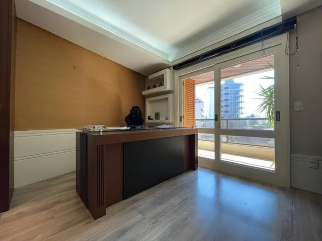 Vista de uma cozinha moderna com ilha e porta de vidro que dá para a varanda.