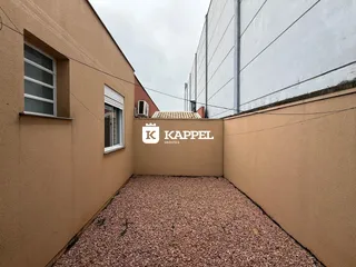 Exterior mostrando um pátio com piso de cascalho entre duas edificações.
