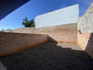 Vista externa de um muro de tijolos e área de terra com cascalho.