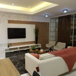 Sala de estar com televisão e estante de madeira.