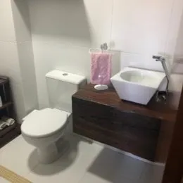 Foto de um banheiro mostrando um vaso sanitário e uma pia brancos.