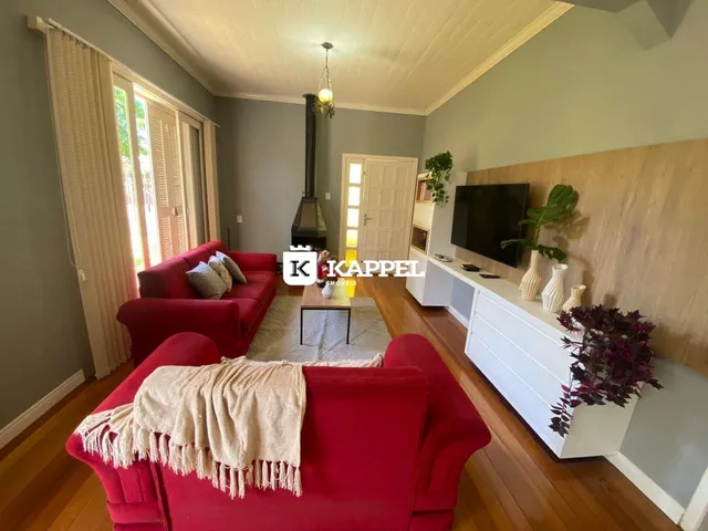 Sala de estar com sofá vermelho e piso de madeira.