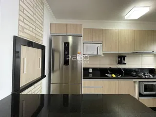 Uma cozinha moderna com armários de madeira clara e bancadas escuras.