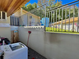 Vista da fachada de uma propriedade com cerca e muro no Brasil.