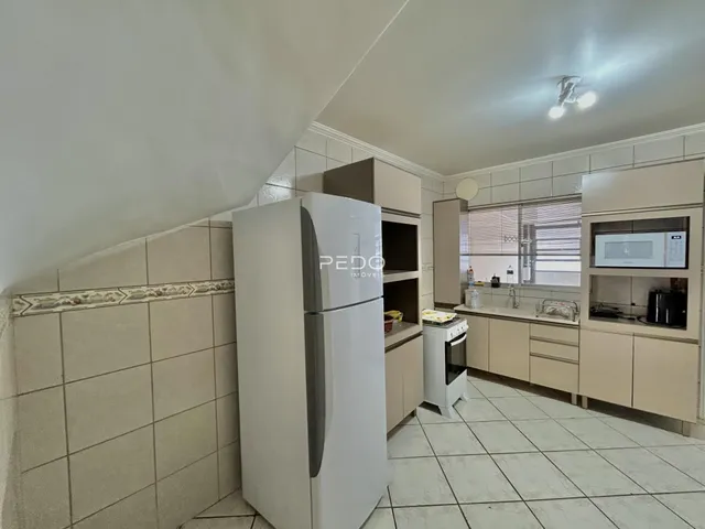 Foto de uma cozinha com armários claros e piso de cerâmica em um imóvel no Brasil.