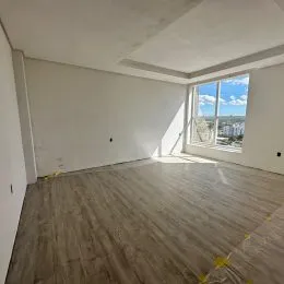 Sala ampla com piso de madeira e grande janela.