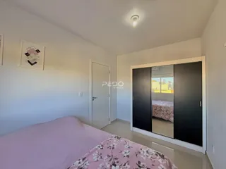 Quarto com cama rosa e paredes brancas.