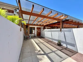Fachada de uma residência com estrutura de madeira sobre um pátio.