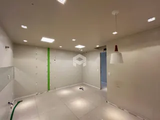 Ambiente interno vazio com paredes brancas e piso claro.