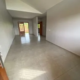 Um corredor interno com piso claro e portas de madeira visíveis.