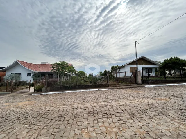 Vista externa de duas casas em Lajeado, Brasil, com cerca e pavimento de paralelepípedos.