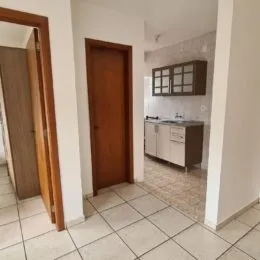 Hall de entrada com portas de madeira e piso de cerâmica clara.