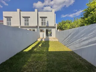 Fachada de uma casa em Lajeado, Brasil, cercada por muros brancos e gramado.