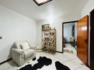 A sala de estar apresenta um sofá claro e um tapete no ambiente.