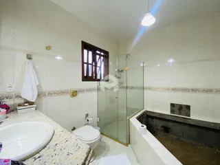 Foto de um banheiro com revestimento cerâmico e box de vidro.