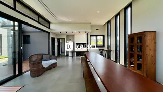 Sala de estar ampla com sofá de vime e piso de madeira clara.