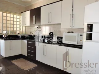 Foto de uma cozinha com armários brancos e bancadas escuras.
