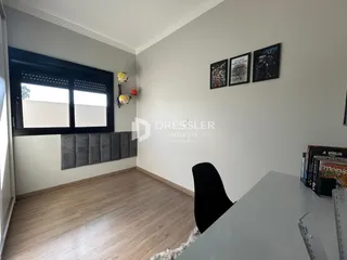 Ambiente interno de uma sala com piso de madeira e janela grande.
