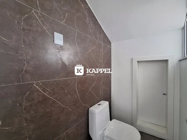 Foto de um banheiro com parede de mármore e vaso sanitário branco.