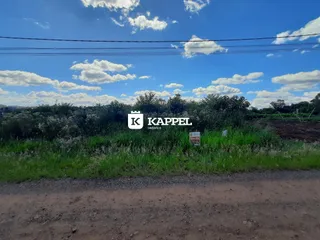 Vista externa de uma área rural com vegetação densa e céu azul.