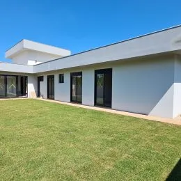 Fachada de uma residência branca com gramado verde em Lajeado.